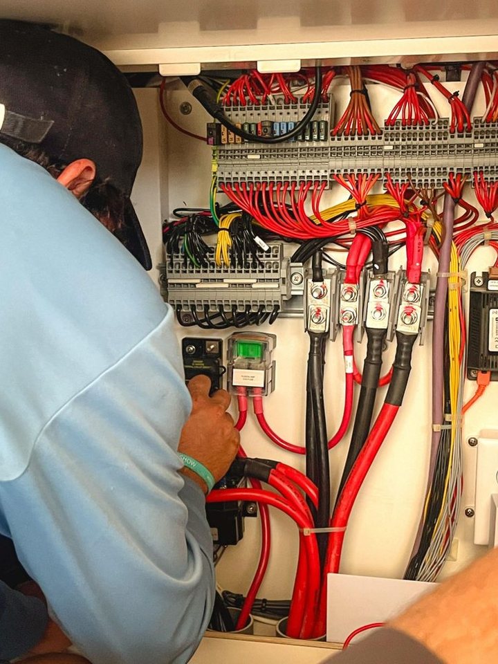 Working on the wiring behind a boat's electrical switchboard