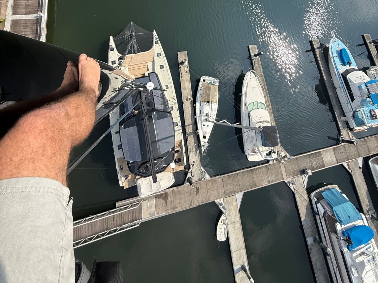 Looking down from the top of the mast at a catamaran in its marina berth